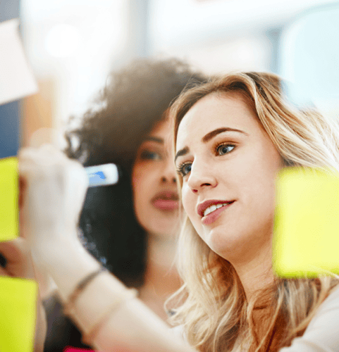 Two women drawing on a post-it note