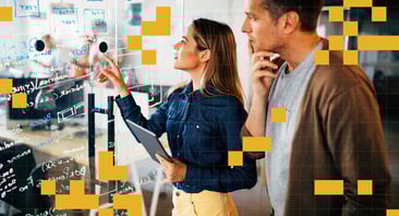 Two people stand at a glass wall with writing and post-its on it.