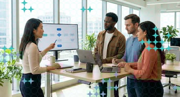 Several people discuss the graphic on a desktop screen at a standing desk.
